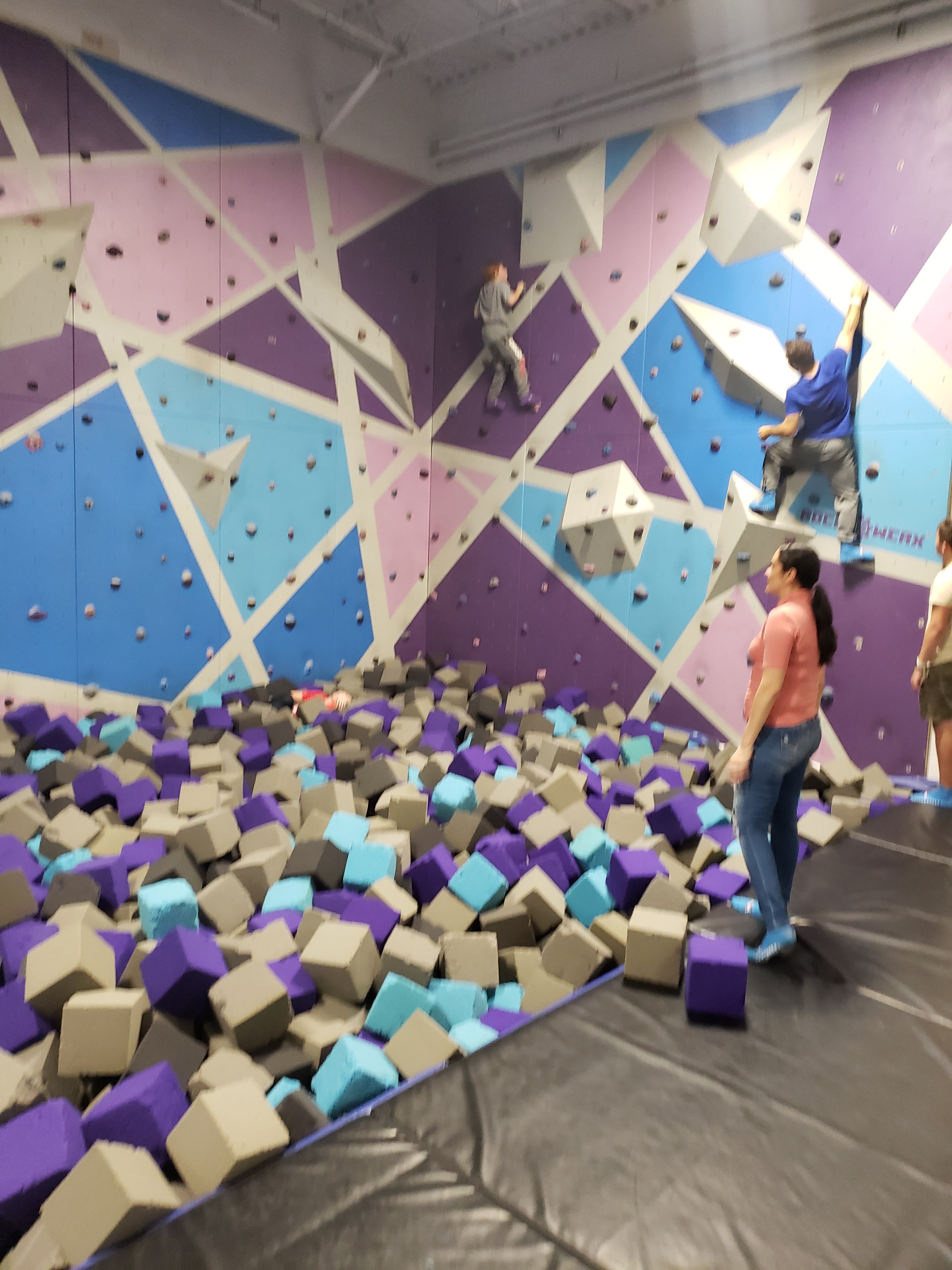 Kids climbing on colorful indoor climbing walls above a foam pit in Tampa, Florida.