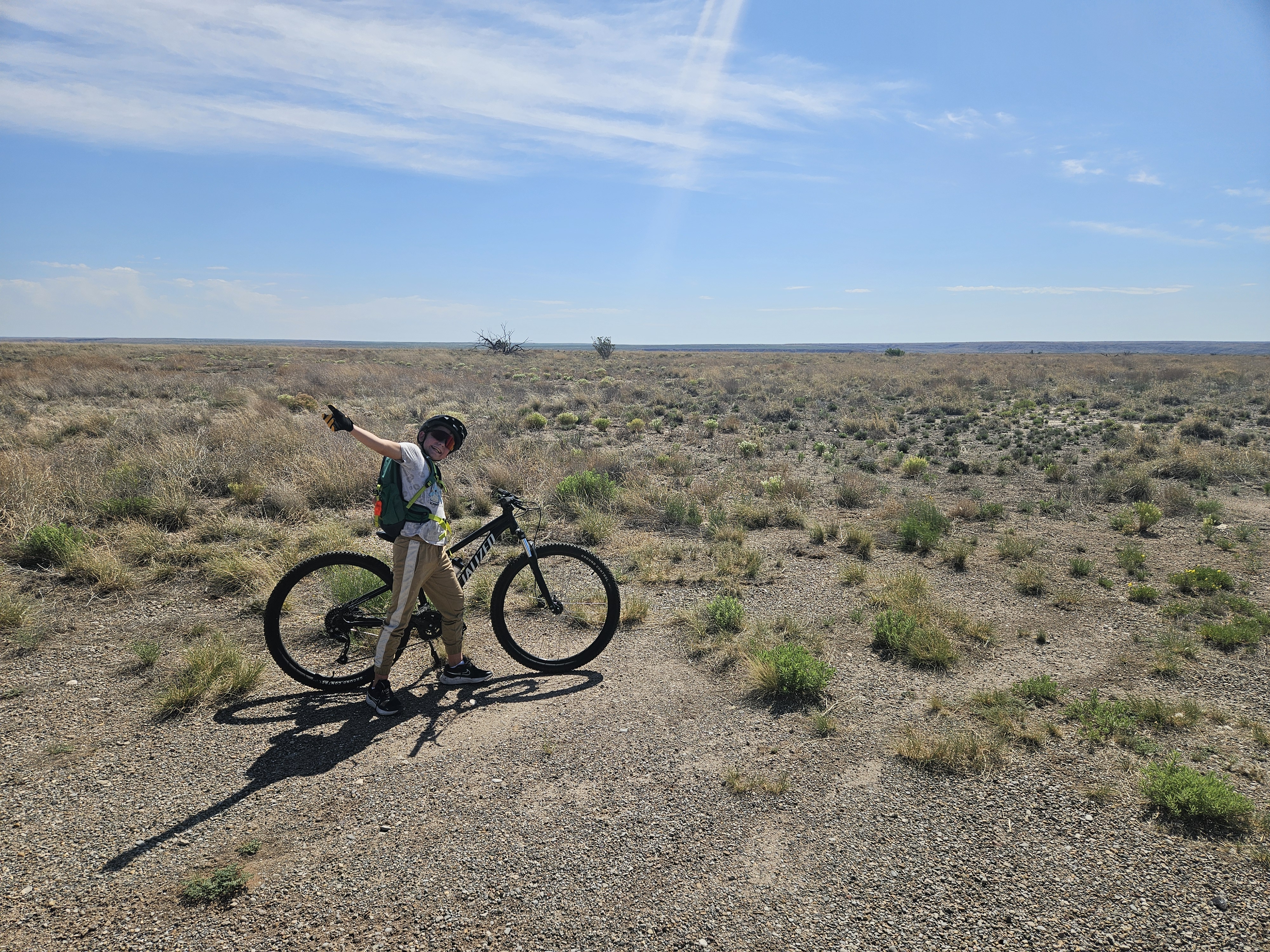 Aden riding a bike through flat desert terrain in New Mexico.